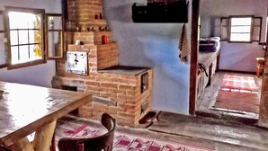 A rustic room with a brick fireplace, a wooden table, and a patterned rug. - Cozo Fantu by Interhome (Vale)