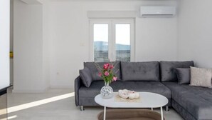 A modern living room with a grey sofa, a white coffee table, and a vase with flowers. - "Luxury Grey house" by Interhome (Domanovići)