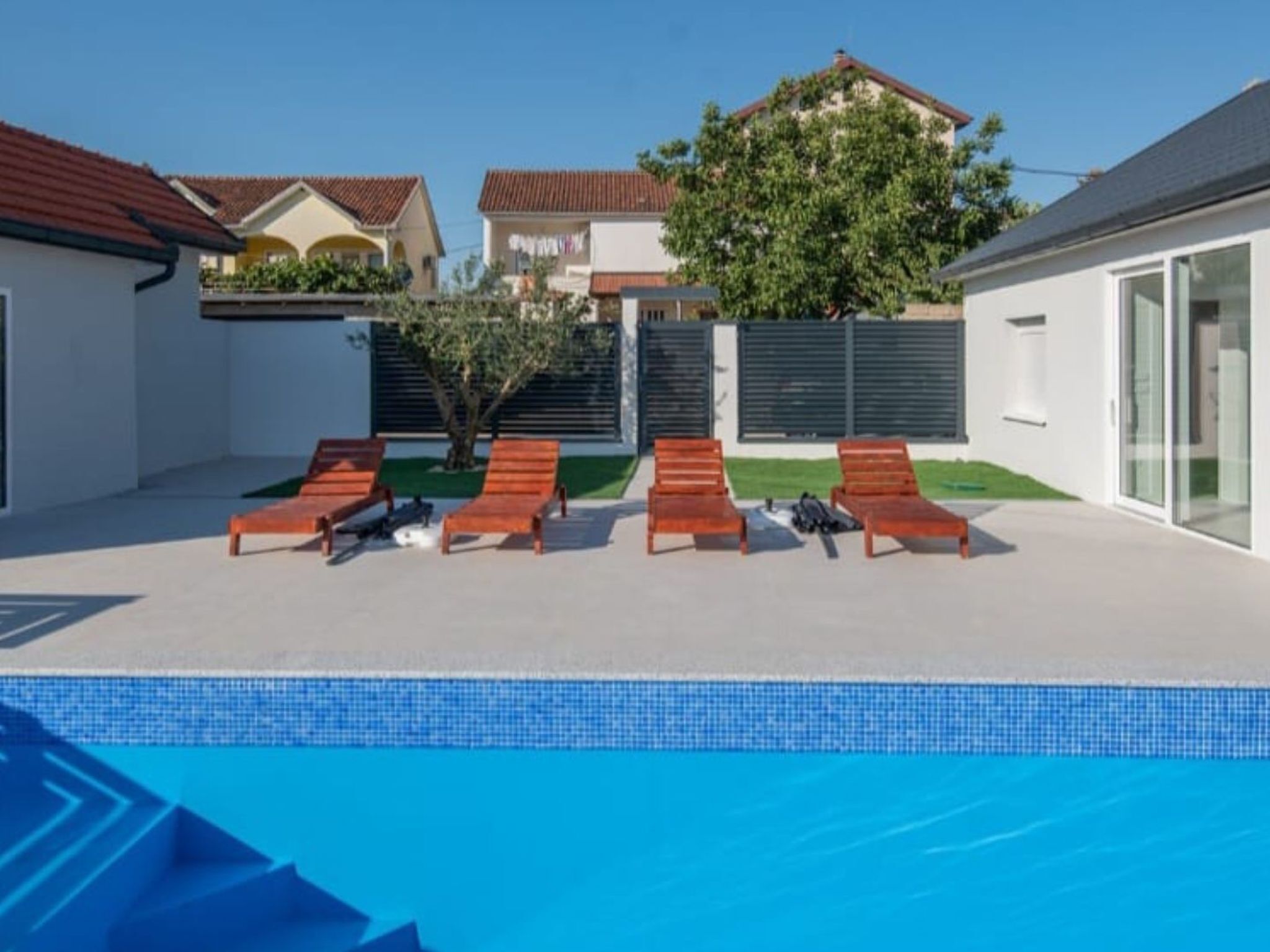 A swimming pool with lounge chairs and a tree in the background.