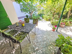 A patio with a table and chairs, surrounded by potted plants and a green door. - Wohnung für 4 Personen, 100m vom Strand entfernt by Interhome (Crikvenica)
