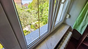 Ein Zimmer mit einem großen Fenster, einem Heizkörper und einem grünen Vorhang.