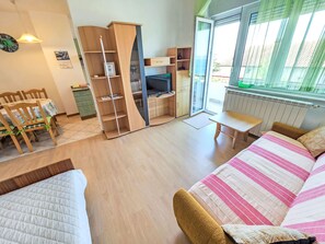 Ein Zimmer mit einem Bett, einem Sofa, einem Fernseher, einem Bücherregal und einem Essbereich.