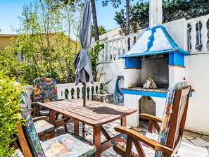 An outdoor patio with a wooden table and chairs, a grill, and a decorative blue chimney. - Haus Marina by Interhome (Plomin)