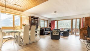 A spacious living area with a wooden ceiling, a dining table with chairs, a sofa, and a fireplace. - Chasa Vista Lischana by Interhome (Scuol)