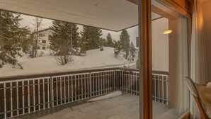 En balkon med udsigt over et sneklædt landskab og træer.