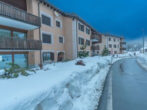 Eine verschneite Straße mit mehrstöckigen Gebäuden, darunter ein Schild mit der Aufschrift 'Cerca Blucca'.