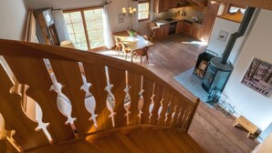 A spacious kitchen with wooden beams, a dining area with a table and chairs, and a staircase with decorative railings. - Chesa Trais FluorsC3 by Interhome (Maloja)