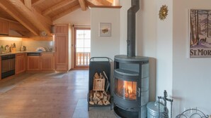 A spacious kitchen with wooden beams, a modern stove, and a dining area with a view of the outdoors. - Chesa Trais FluorsC3 by Interhome (Maloja)