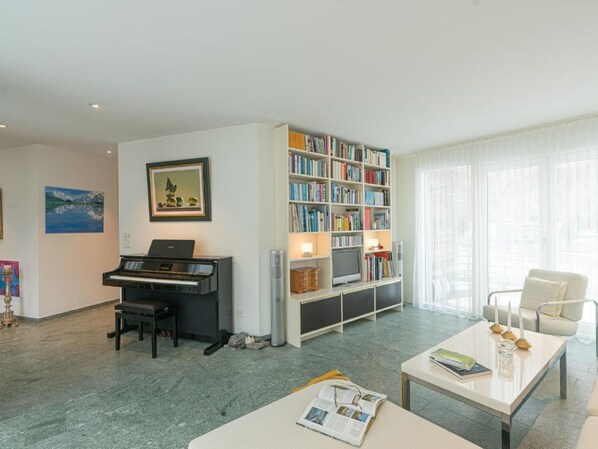 Ett vardagsrum med ett piano, en bokhylla, en tv och ett soffbord.