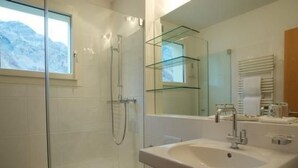 Ein modernes Badezimmer mit einer Duschkabine aus Glas, einem weißen Waschbecken und einem großen Spiegel.