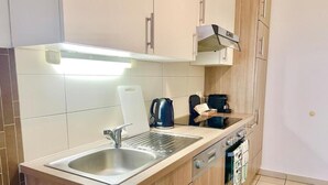 A modern kitchen with a built-in sink, a kettle, a coffee maker, and wooden cabinets. - Charming Flat by Interhome (Vienna / 10. District)