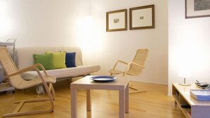 A minimalist living room with a white sofa, two wicker chairs, a small table with a blue plate, and a lamp on a cart. - Residenz Alpenrose22 by Interhome (Sils Maria)