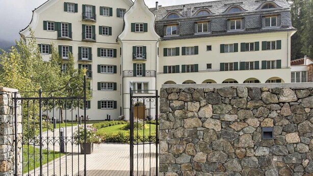 A large, multi-story building with a stone wall entrance, multiple balconies, and a well-maintained garden area. - Residenz Alpenrose22 by Interhome (Sils Maria)