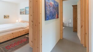 Une chambre avec un lit en bois, un tapis et un tableau accroché au mur.