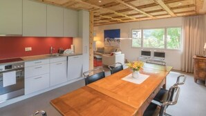 Une cuisine moderne avec des meubles blancs, un pare-feu rouge et une table à manger en bois, accompagnée de chaises.