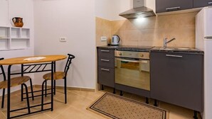 Une cuisine compacte comprenant une table à manger, des chaises, une cuisinière, un four et un évier.