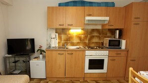 Eine kleine Küche mit Holzausstattung, einer Mikrowelle, einem Herd und einem Kühlschrank.