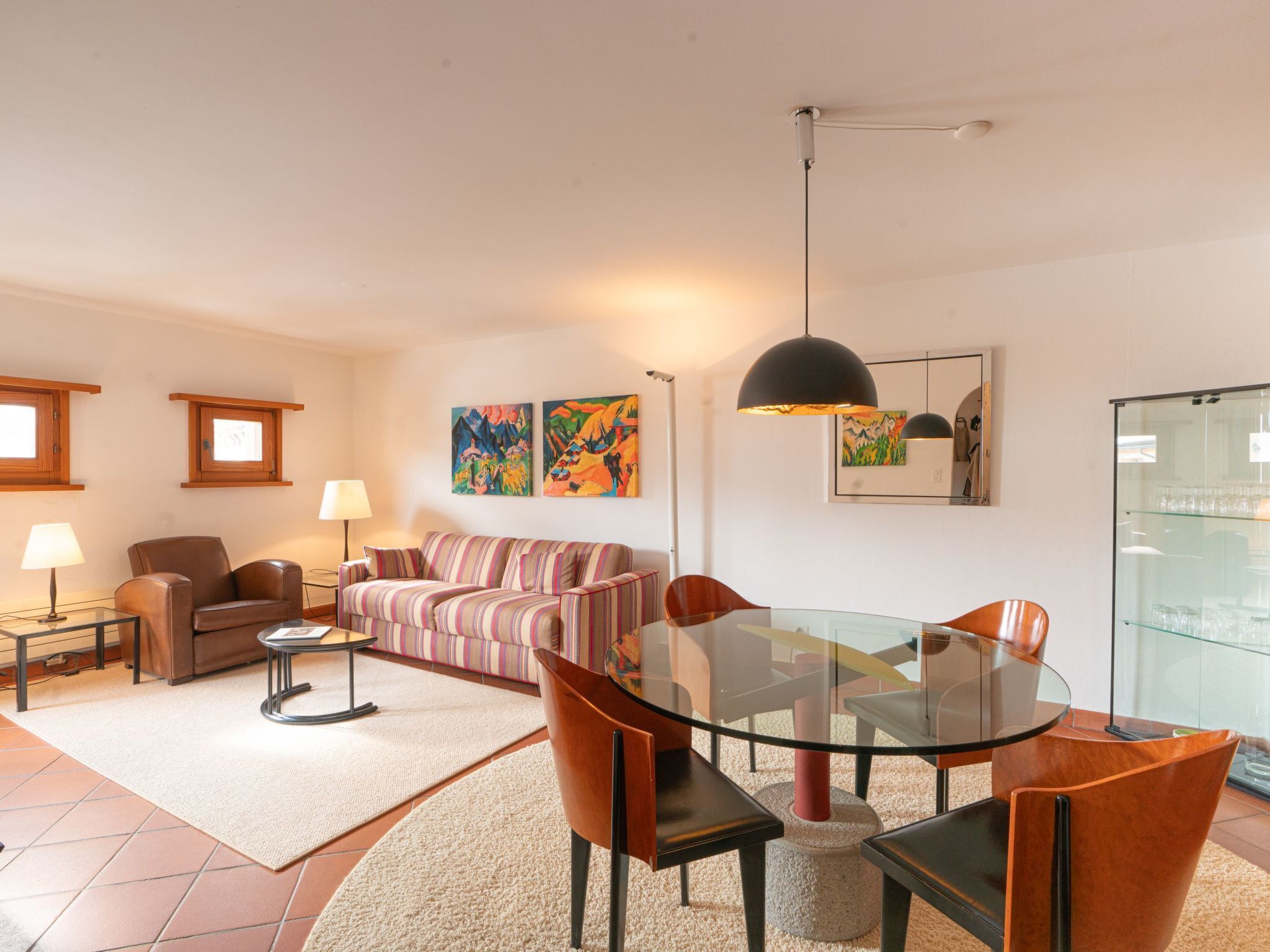 Una sala de estar moderna con una mesa de comedor de vidrio, sofás de cuero y un cuadro grande en la pared.