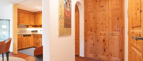 Una cuina moderna amb armaris de fusta, una zona de menjador amb una cadira i una porta de fusta gran.
