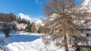 Ett snötäckt landskap med en byggnad, träd och en klar himmel.
