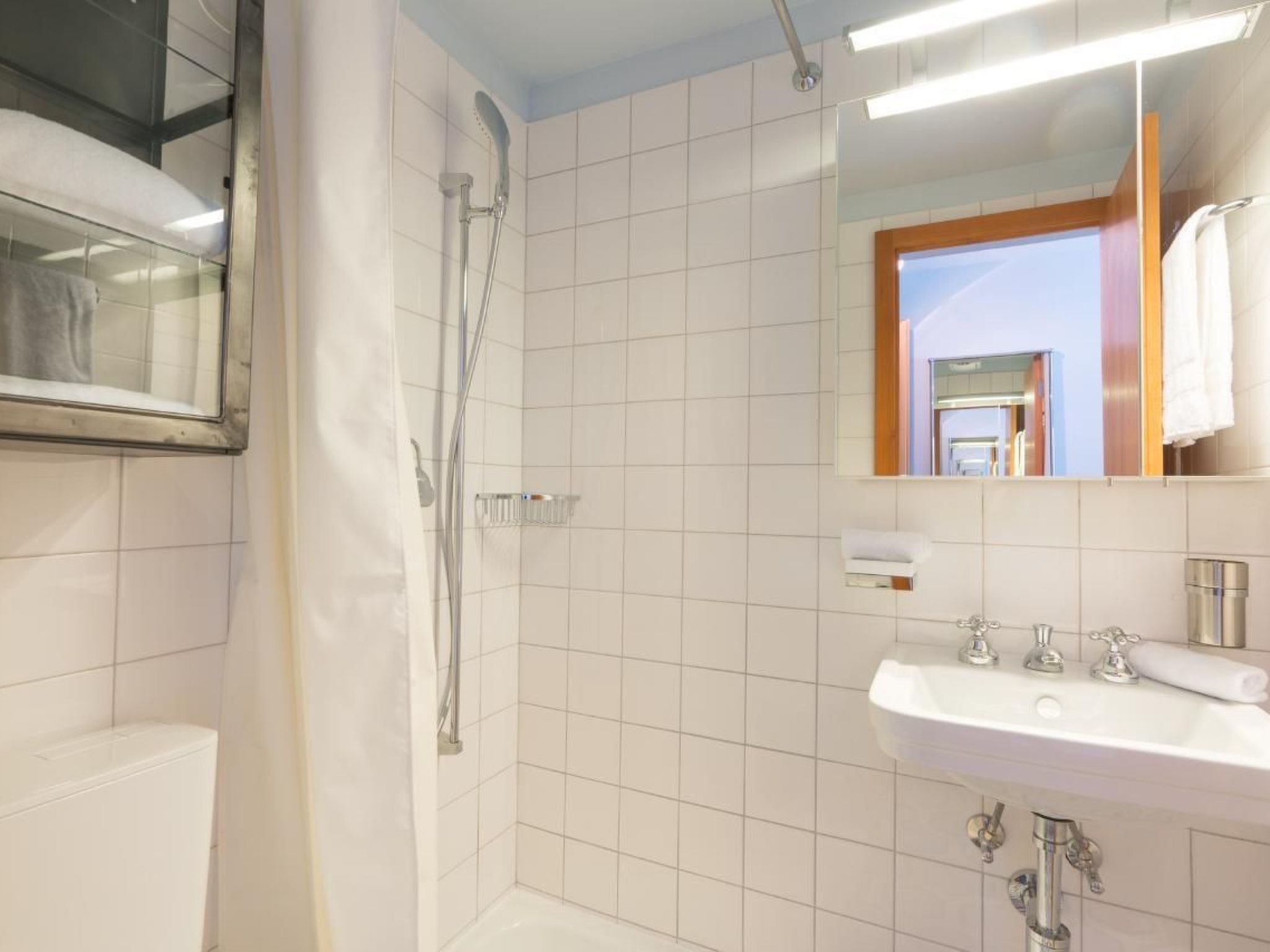 A bathroom with a shower, a sink, and a mirror.