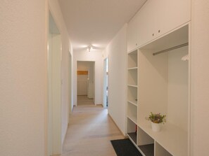 A narrow hallway with a wooden floor leading to a room with a white wardrobe and a potted plant. - Chesa Maria 7 by Interhome (Sils Maria)
