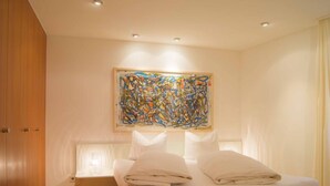 Un dormitorio moderno con una cama, una mesita de noche y un cuadro abstracto grande en la pared.