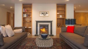 Una sala de estar con chimenea, dos sofás, una mesa de centro y estanterías.