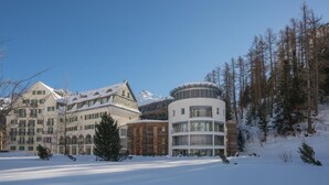 Un hotel con varias edificaciones, incluyendo una estructura central grande con techo circular y varias construcciones más pequeñas con tejados cubiertos de nieve.