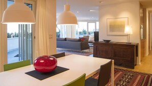 Una sala de estar moderna con un sofá, una mesa de comedor con sillas e iluminación colgante.
