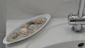 Uma pia de banheiro com cuba branca e torneira cromada.