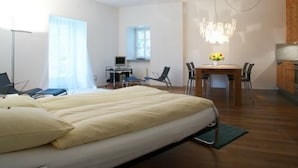 Quarto de hotel moderno com uma cama grande, uma escrivaninha e uma área de refeições.