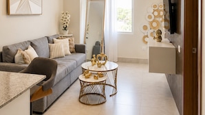 A modern living room with a grey sofa, a coffee table, and a TV mounted on a wooden panel. - Playa y Sol cercano al Aeropuerto (Boca Chica)