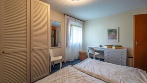 A bedroom with two beds, a desk, a chair, and a wardrobe. - Selvas 12 by Interhome (Sils Maria)