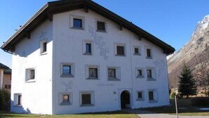 A multi-story building with a symmetrical facade, multiple windows, and a central entrance. - Selvas 12 by Interhome (Sils Maria)