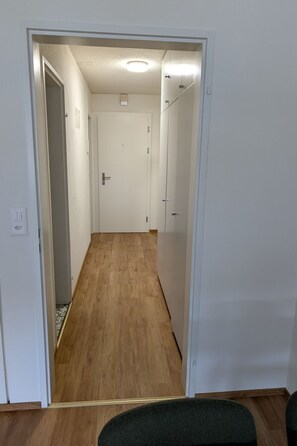 A hallway with wooden flooring and white walls, leading to a door at the end. - Apartment Barga by Interhome (Davos)