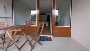 Une pièce avec une table et des chaises en bois, une porte-fenêtre coulissante et une vue sur une montagne.