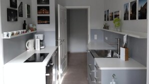 A modern kitchen with white cabinetry, a coffee machine, and a sink. There are framed pictures on the walls and a door leading to another room. - Apfeltraum by Interhome (Dresden)