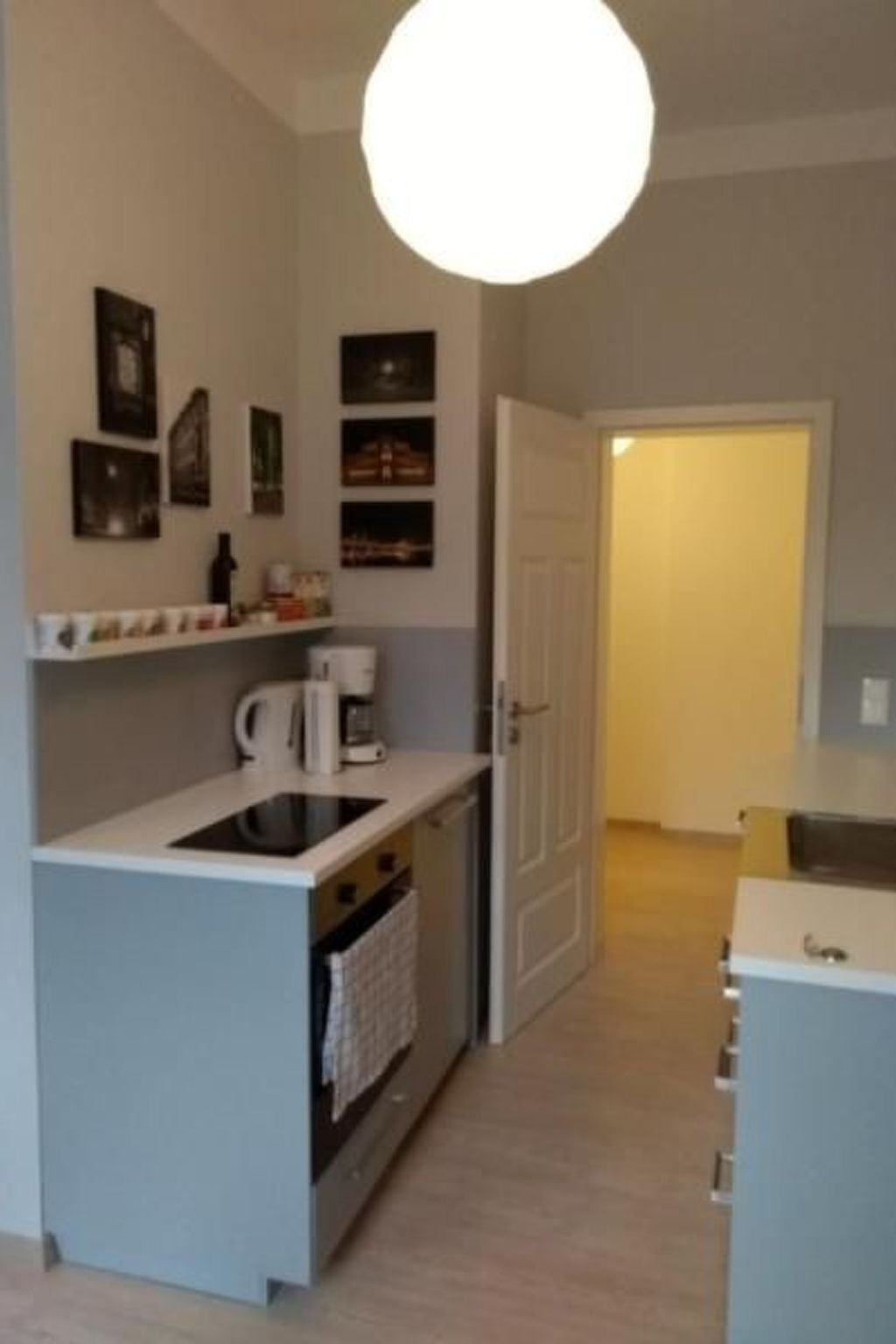 A compact kitchen with a central island, a coffee machine, and a door leading to another room.