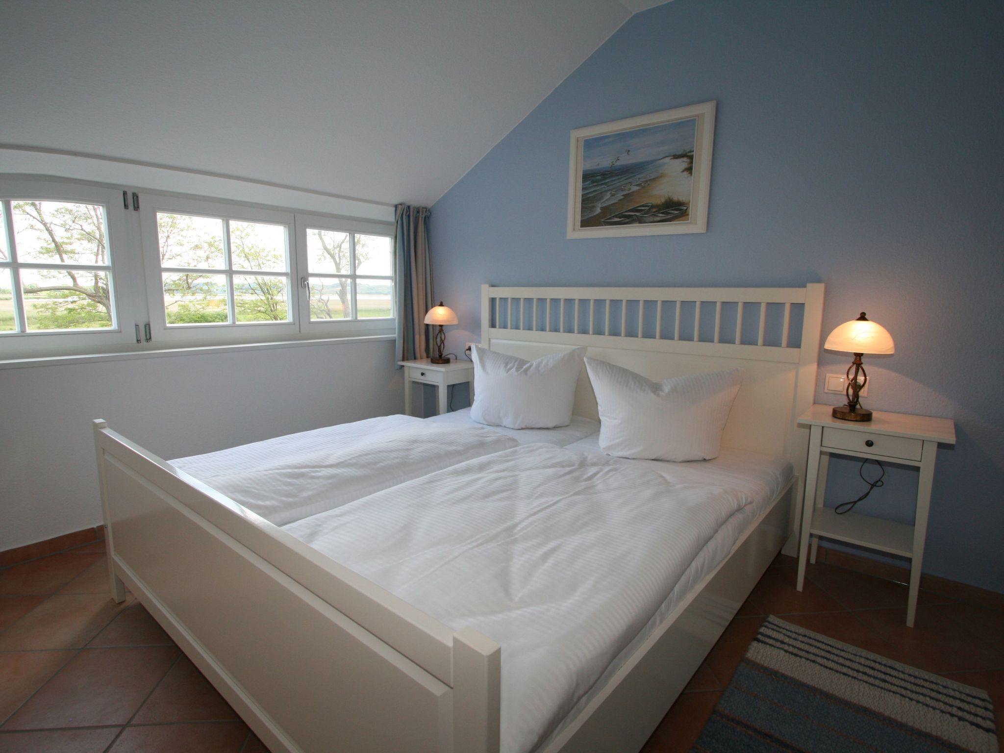 Une chambre à coucher avec un grand lit, deux tables de chevet, une commode, une fenêtre et un tableau au mur.
