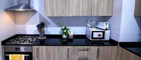 Una cocina equipada con estufa a gas, horno, microondas y armarios de madera.