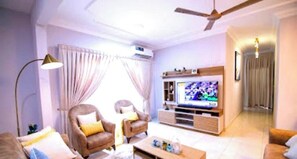 A living room with a sofa, armchairs, a coffee table, a TV, and a ceiling fan. - 5-Star Comfort Luxury-Destini Homes-24/7 Security (Sakumono)