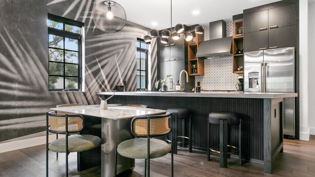 Una cucina moderna con isola centrale, sgabelli da bar e tavolo da pranzo.
