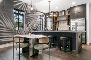 Una cocina moderna con una isla central, taburetes de bar y una mesa de comedor.