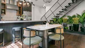 Una cucina moderna con isola centrale, sgabelli da bar e una scala.