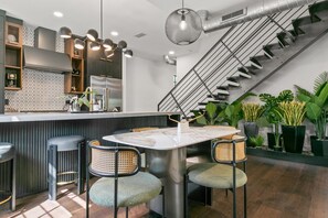 Una cocina moderna con una isla central, taburetes de bar y una escalera.