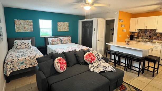 A compact living space with a sofa, two beds, a kitchenette, and a ceiling fan. - Casita Cortes is quiet, cozy and centrally located in Tampa. (Tampa)