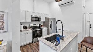 Una cocina moderna con armarios blancos, electrodomésticos de acero inoxidable y encimera de mármol.