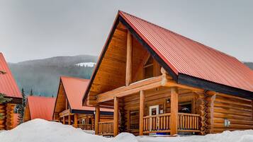 A log cabin with a red roof and wooden exterior, surrounded by snow.
