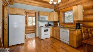A wooden cabin kitchen with a refrigerator, stove, microwave, and dishwasher.